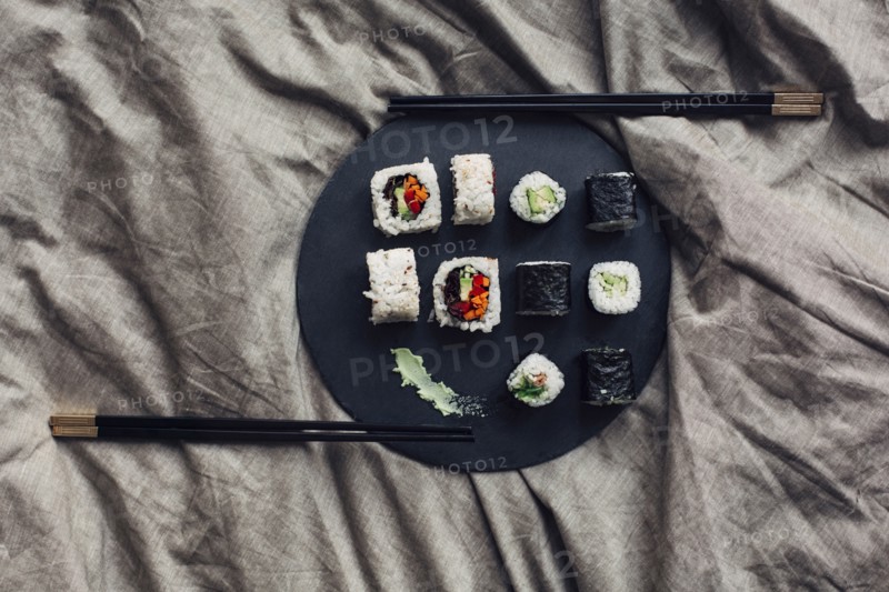Close up of sushi platter with chopsticks in bed