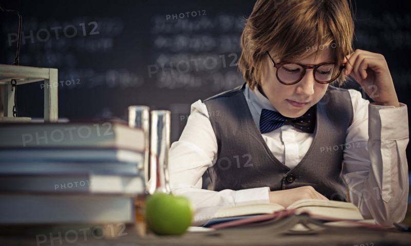 Student reading book at desk in classroom