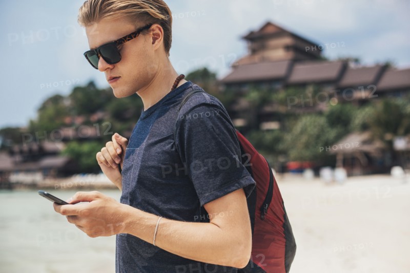 Caucasian man using cell phone on beach