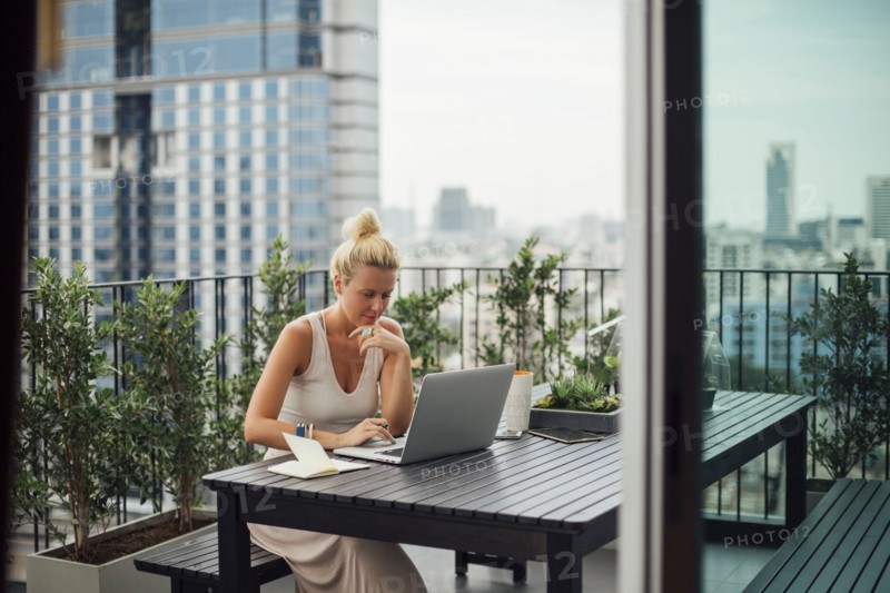Caucasian woman using laptop on balcony