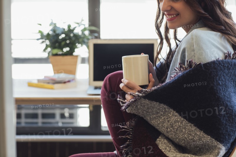 Caucasian woman in blanket drinking cup of coffee