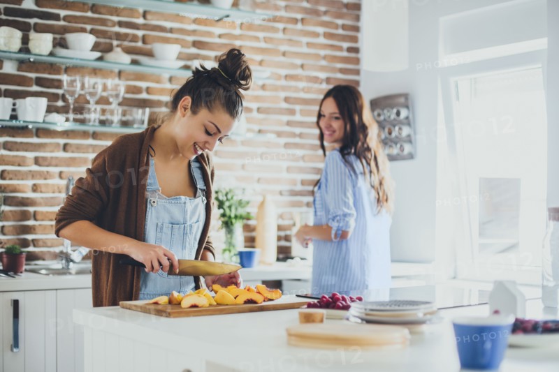 Caucasian women chopping fruit in kitchen
