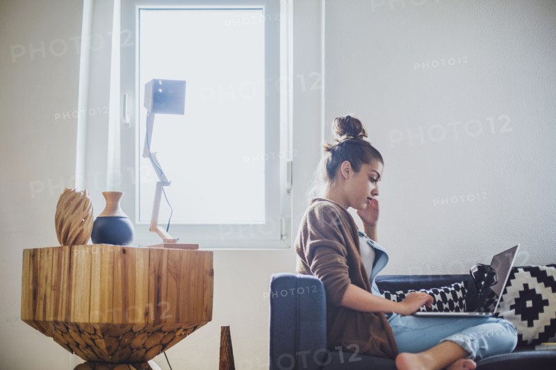 Caucasian woman using laptop on sofa