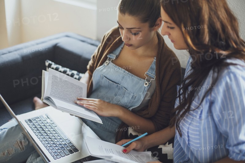 Caucasian women studying on sofa
