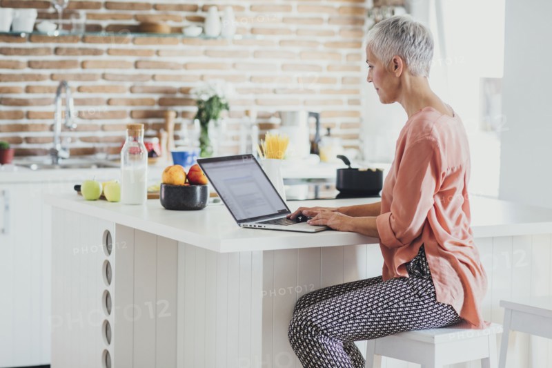 Older Caucasian woman using laptop in kitchen