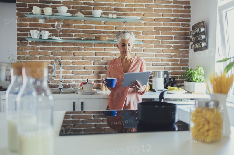 Older Caucasian woman using digital tablet in kitchen