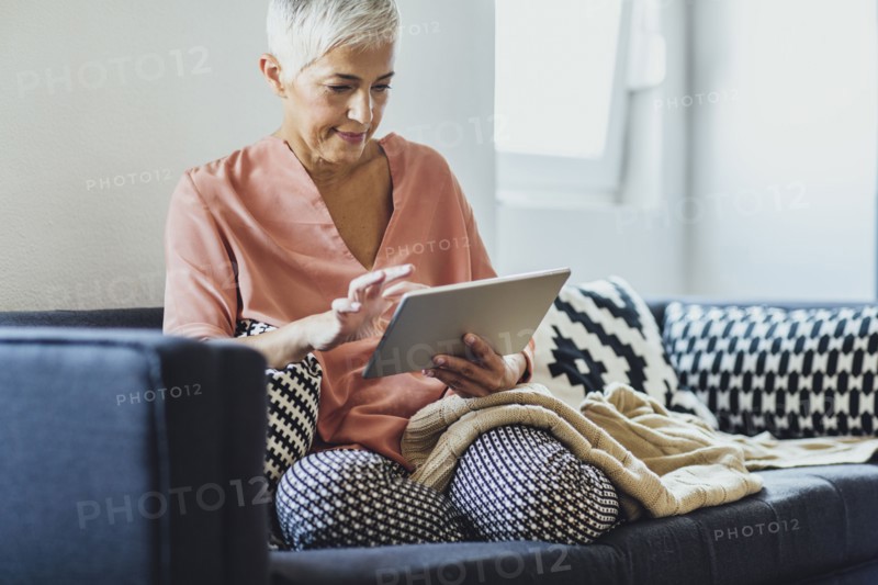 Older Caucasian woman using digital tablet on sofa