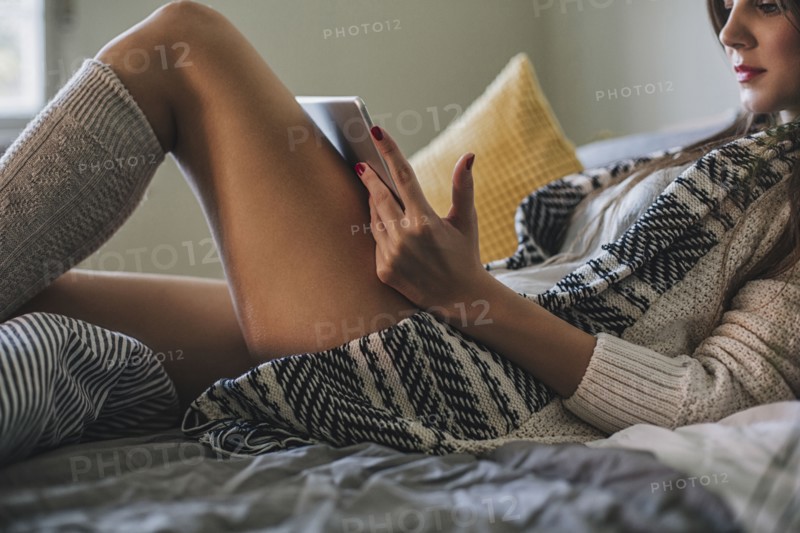 Woman reading digital tablet on bed