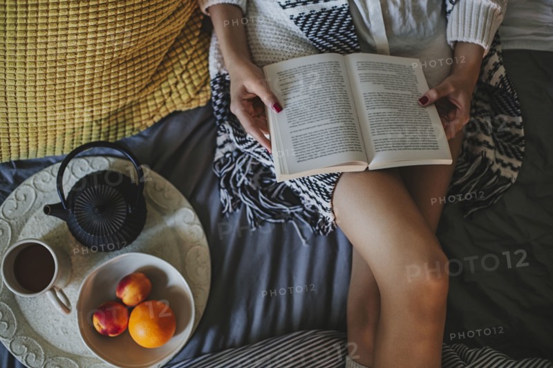 Woman reading book on bed