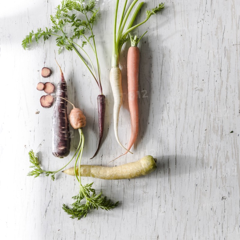 Variety of carrots on white wooden table