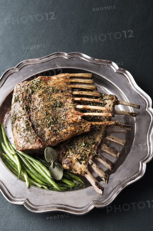 Rack of lamb and green beans on silver platter