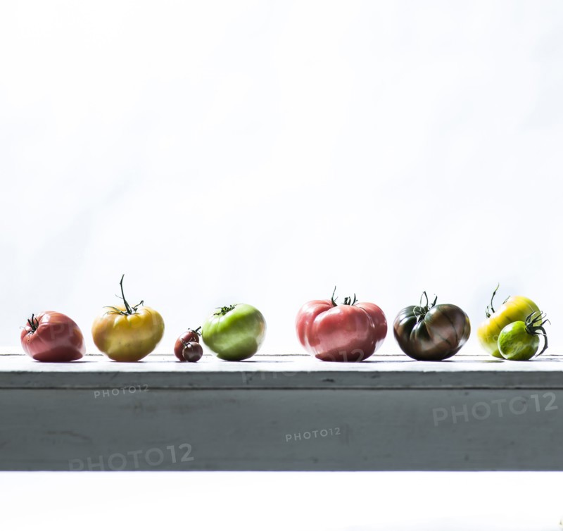 Row of fresh tomatoes on wooden table