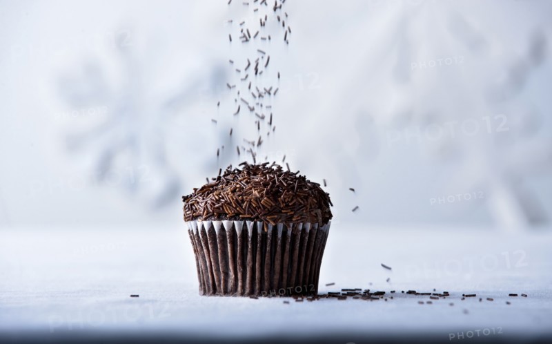 Brown sprinkles falling on chocolate cupcake
