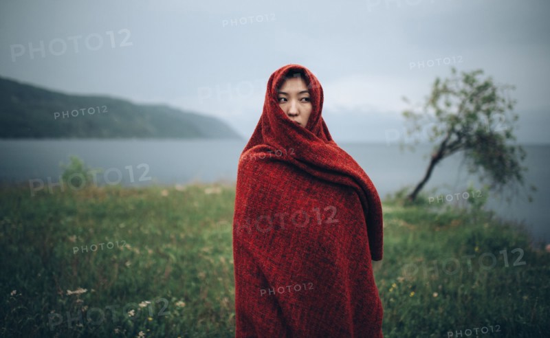 Caucasian woman wrapped in blanket in rural field
