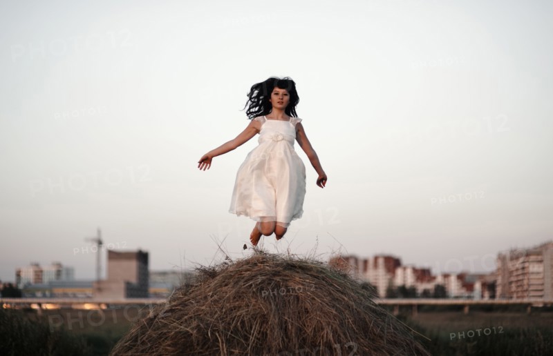 Caucasian woman jumping on haystack