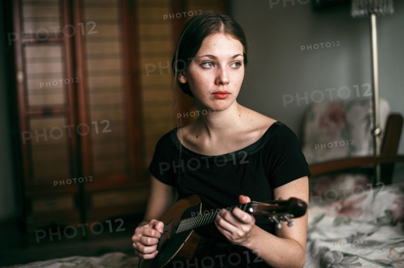 Caucasian woman playing ukulele in bedroom