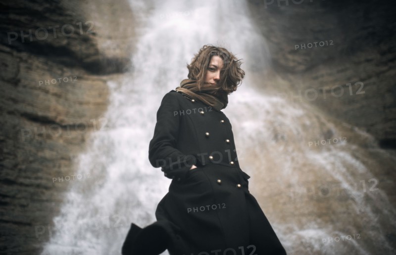 Caucasian woman standing under waterfall