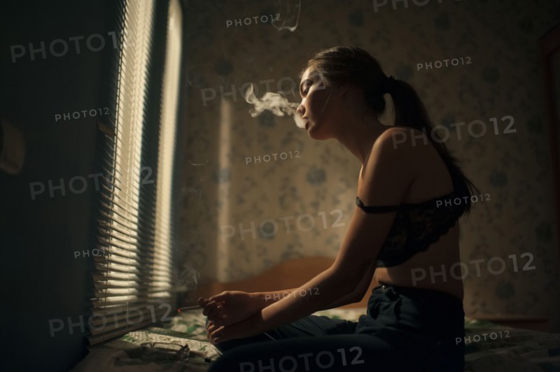 Caucasian woman smoking in bedroom