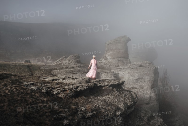 Caucasian woman standing on misty rock formation