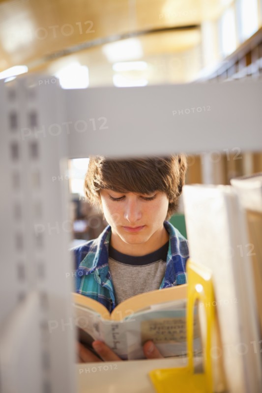Mixed race boy reading book in library
