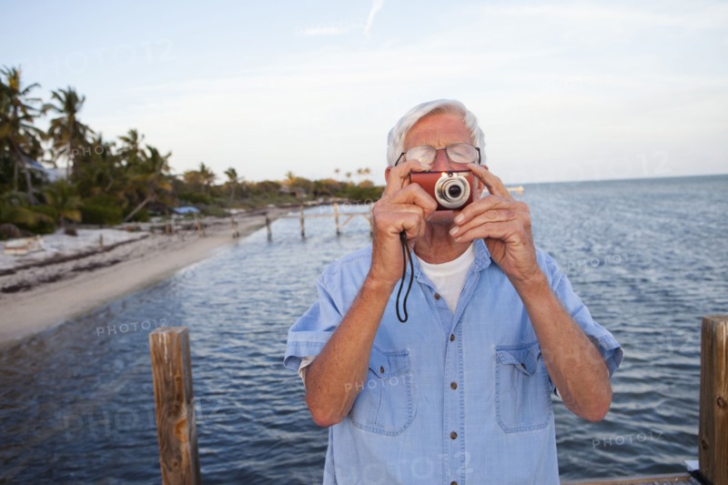 Caucasian man taking photographs on beach