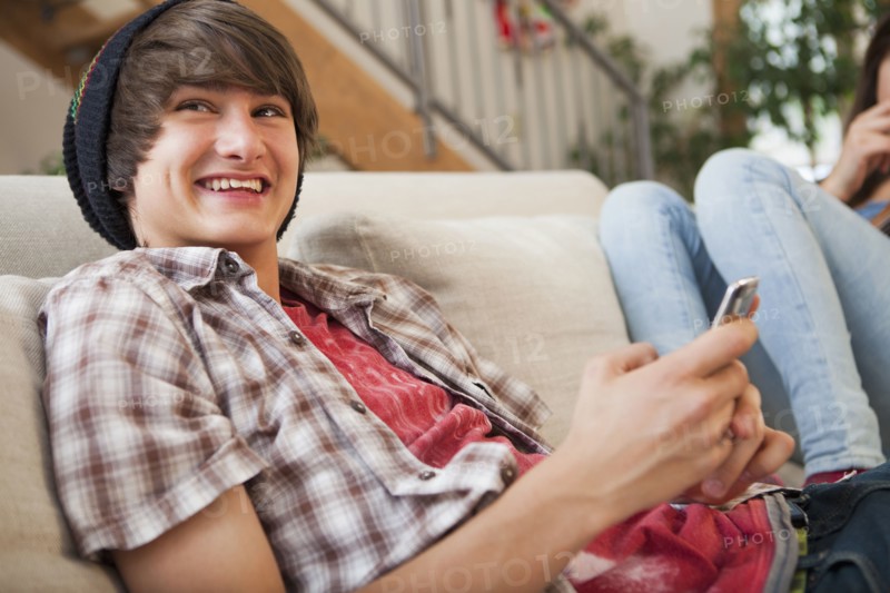 Mixed race boy using cell phone on sofa