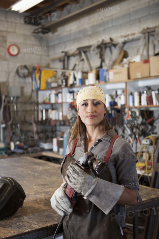 Hispanic factory worker holding metal fabricator