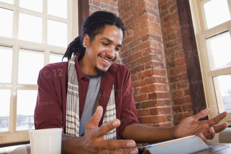 Mixed race man using digital tablet in coffee shop