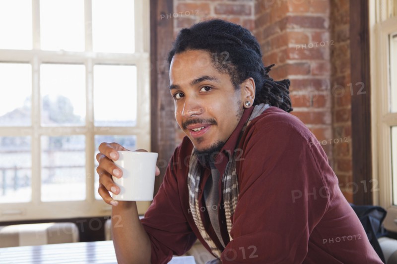 Mixed race man drinking coffee in coffee shop