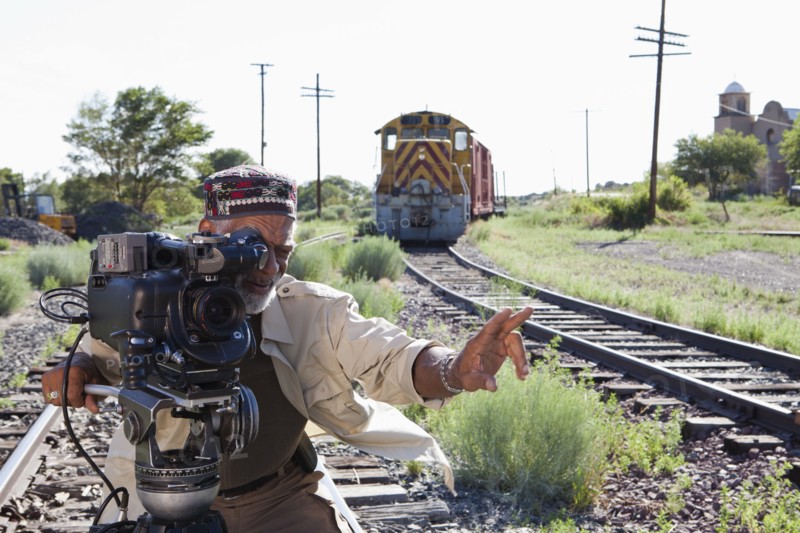 African American man with film camera near railroad tracks