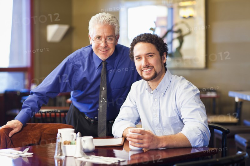 Businessmen smiling together in cafe