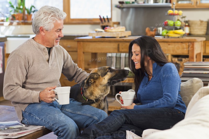 Hispanic couple petting dog in living room