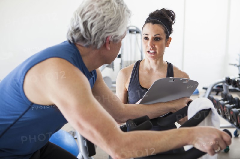 Older Hispanic man working with trainer in gym