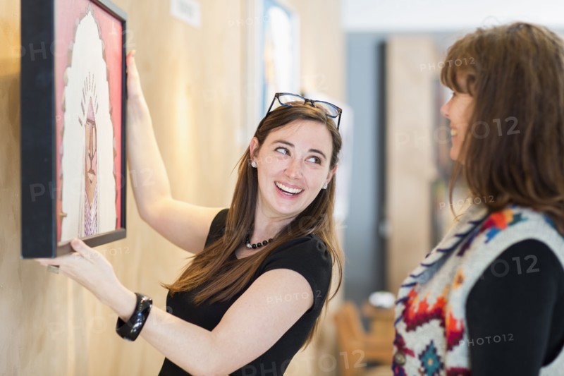 Women hanging painting on wall