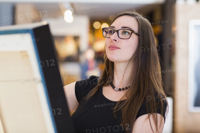 Caucasian woman examining painting in art gallery