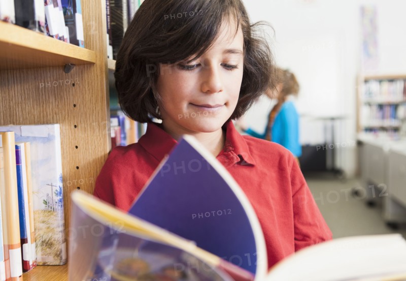 Caucasian boy reading book in library
