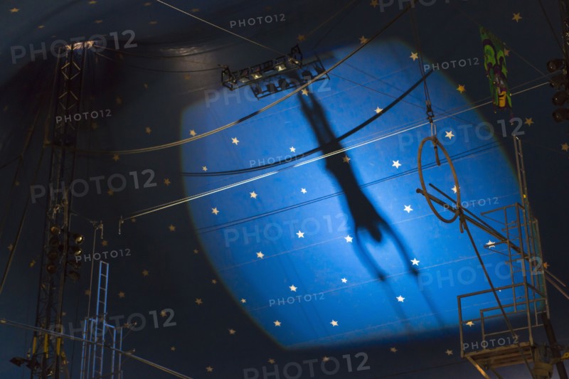 Shadow of acrobat in spotlight on wall