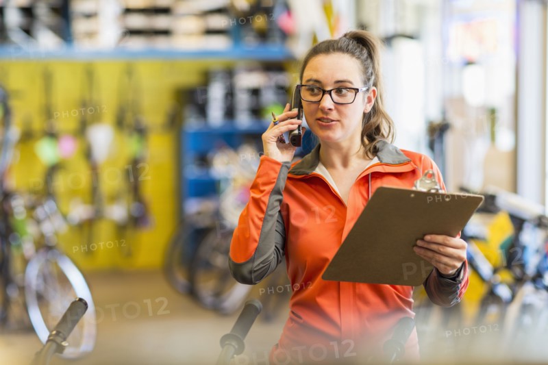Caucasian woman talking on telephone in bicycle shop