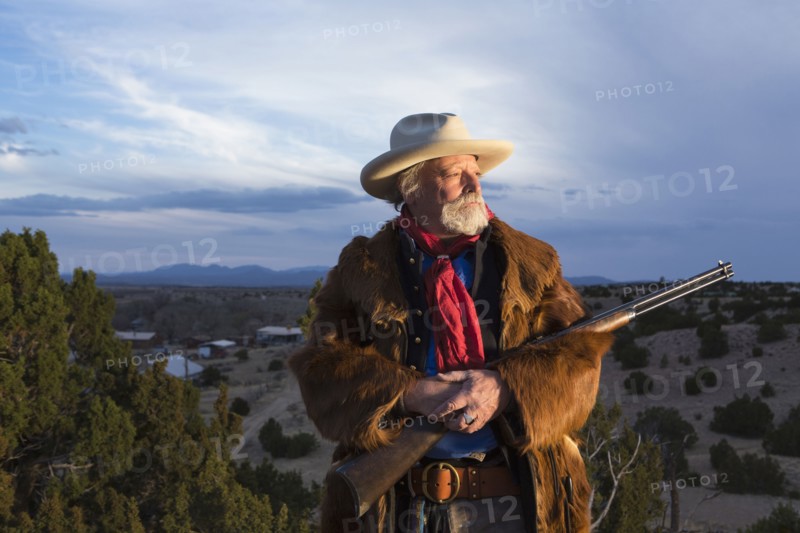 Caucasian man holding gun in dusty landscape