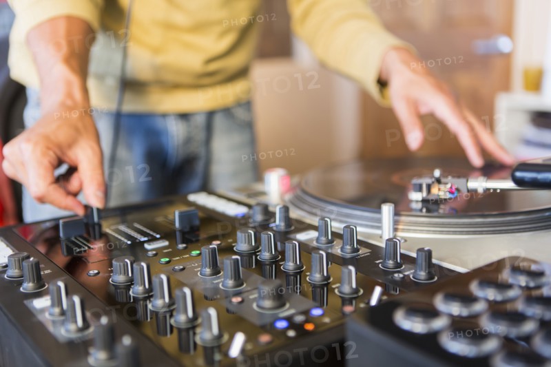 Mixed race disc jockey using turntable in studio