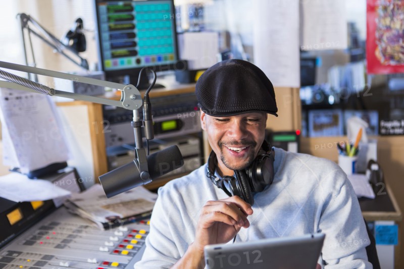 Mixed race disc jockey using tablet computer in studio