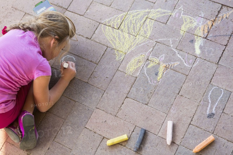 Caucasian girl drawing with chalk on brick
