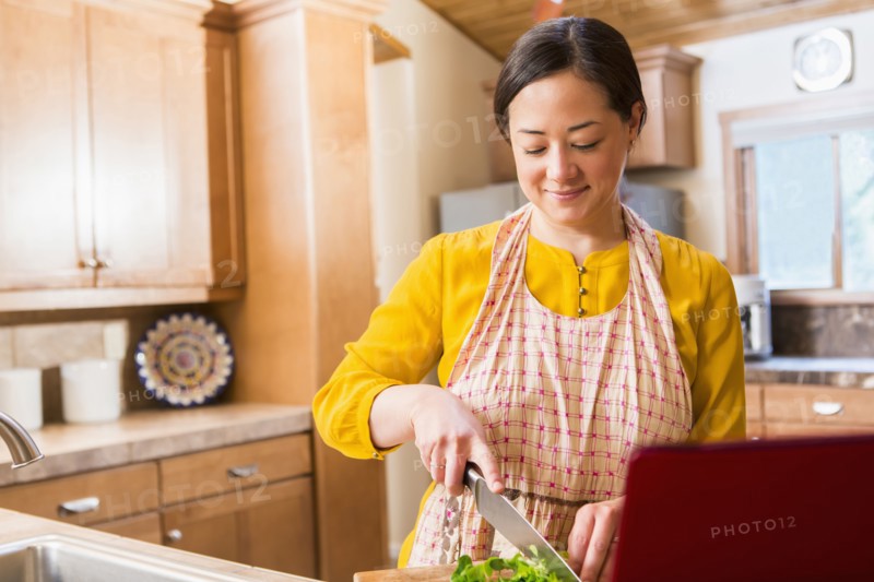 Mixed race woman cooking in kitchen