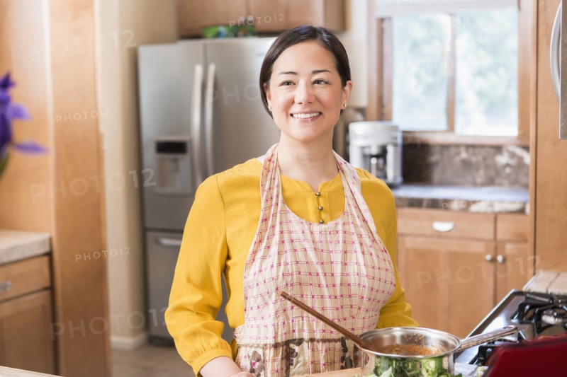 Mixed race woman cooking in kitchen