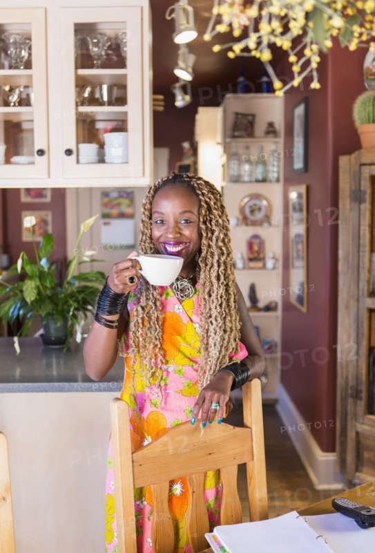 African American woman having cup of coffee in kitchen
