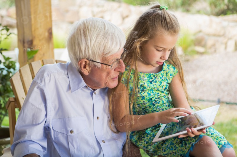Caucasian man using digital tablet with granddaughter