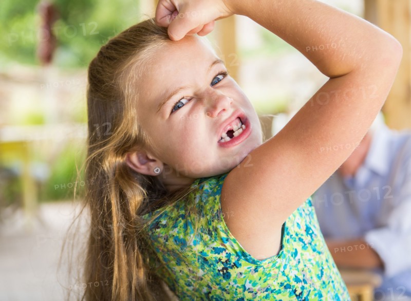 Caucasian girl showing missing teeth and flexing biceps