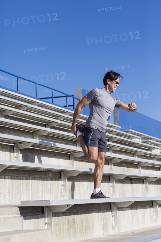 Hispanic athlete stretching on bleachers