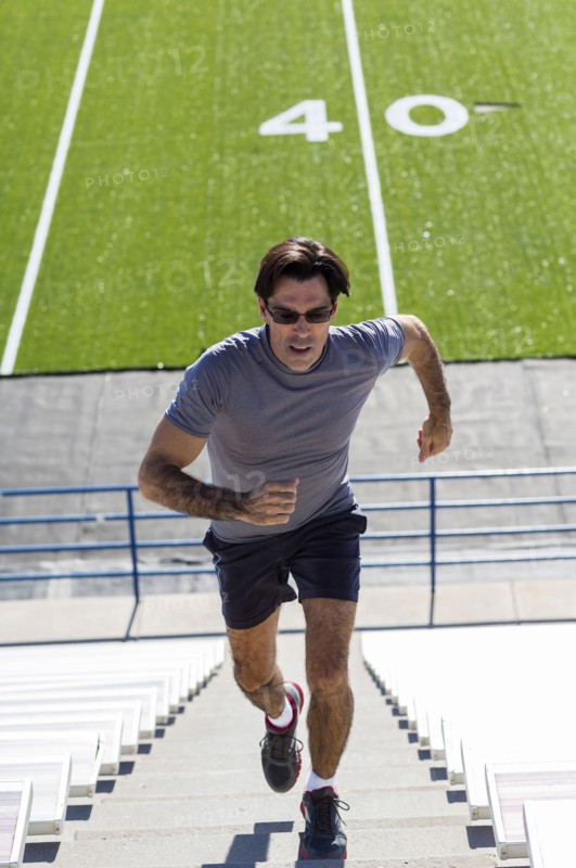 Hispanic athlete running on bleacher steps