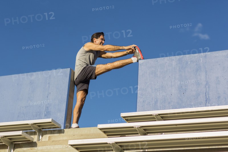 Hispanic athlete stretching on bleachers
